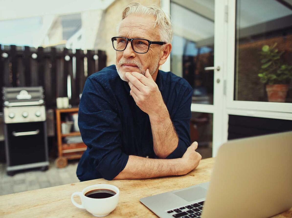 Mand med computer og kop kaffe