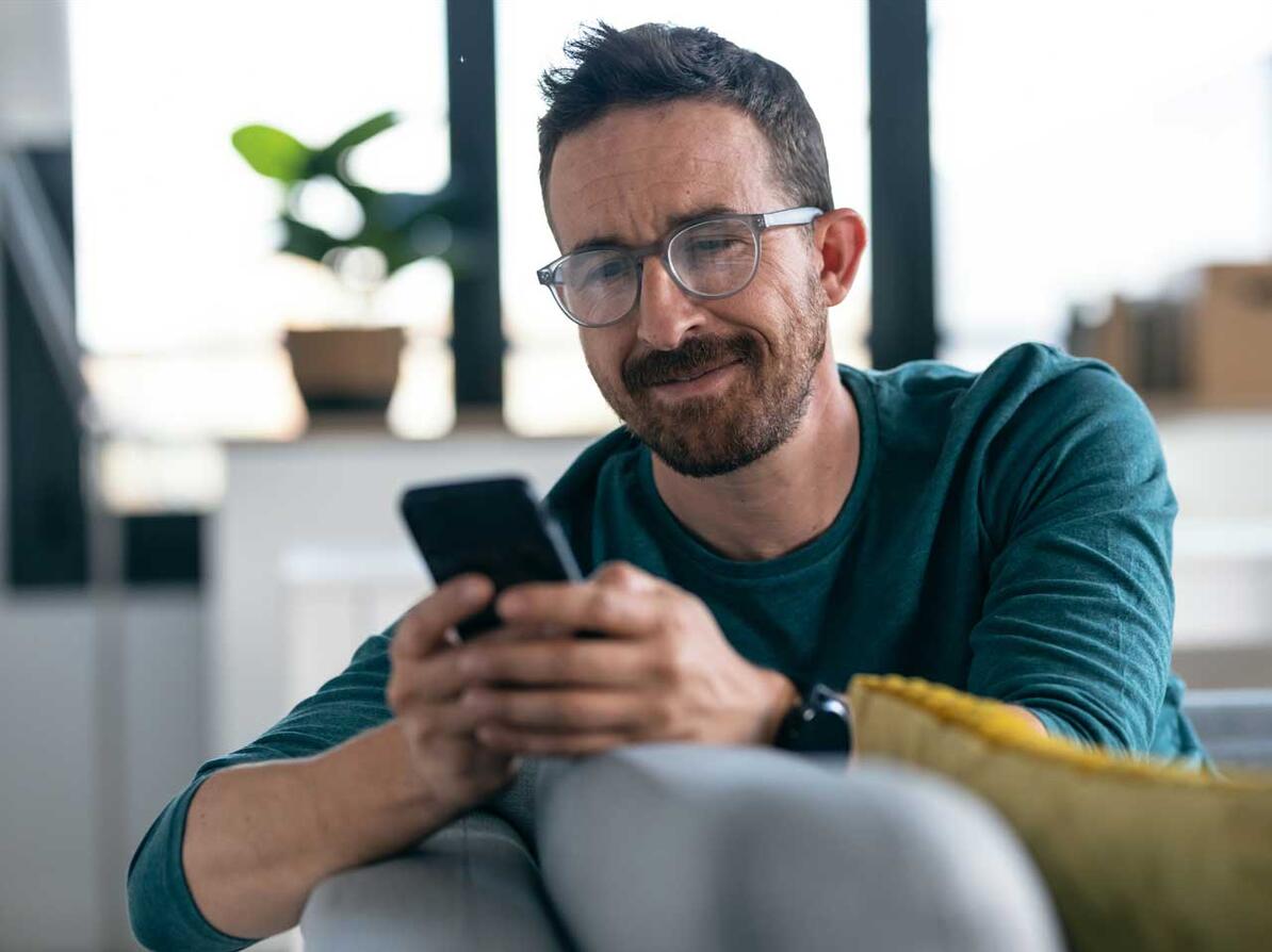 Mand med mobiltelefon ser skeptisk på en sms