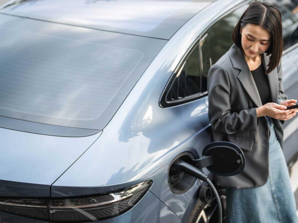 Kvinde står ved elbil, som er ved at blive opladet