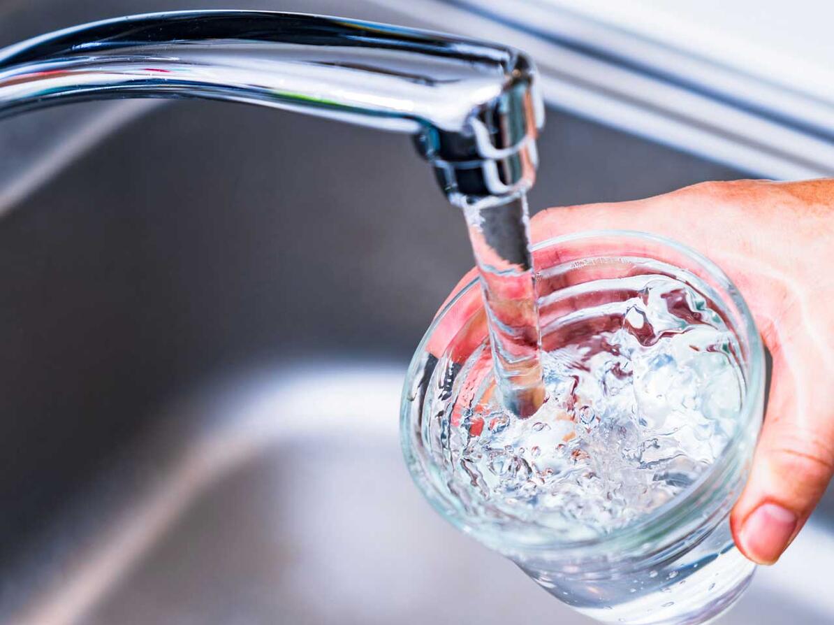 Vand kommer ud af vandhane og ned i glas