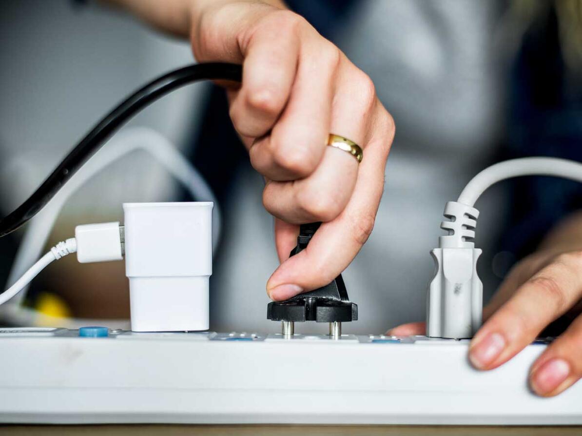 Hånd stikker stik i stikkontakt