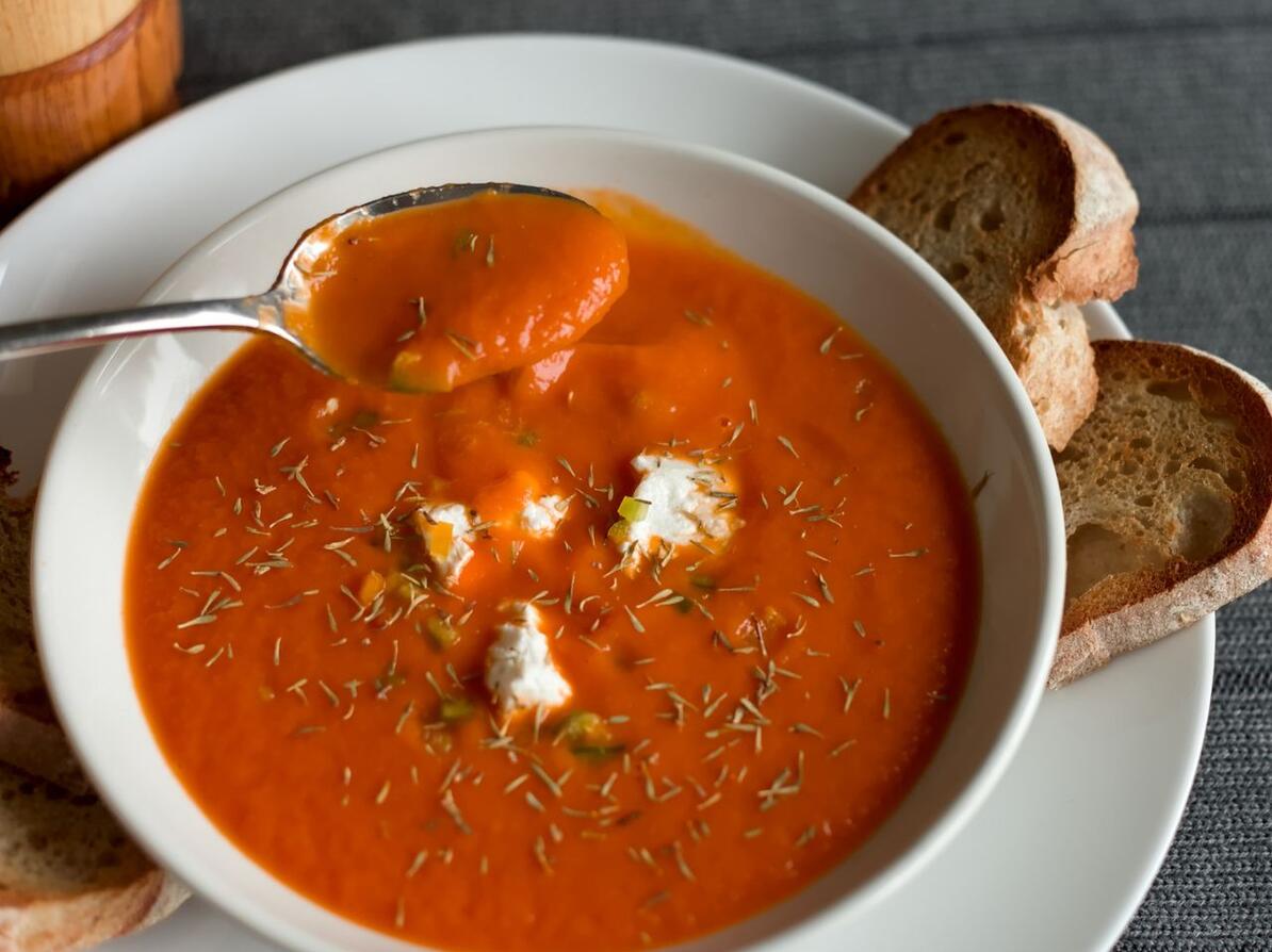 Tomatsuppe i dyb tallerken med brod til