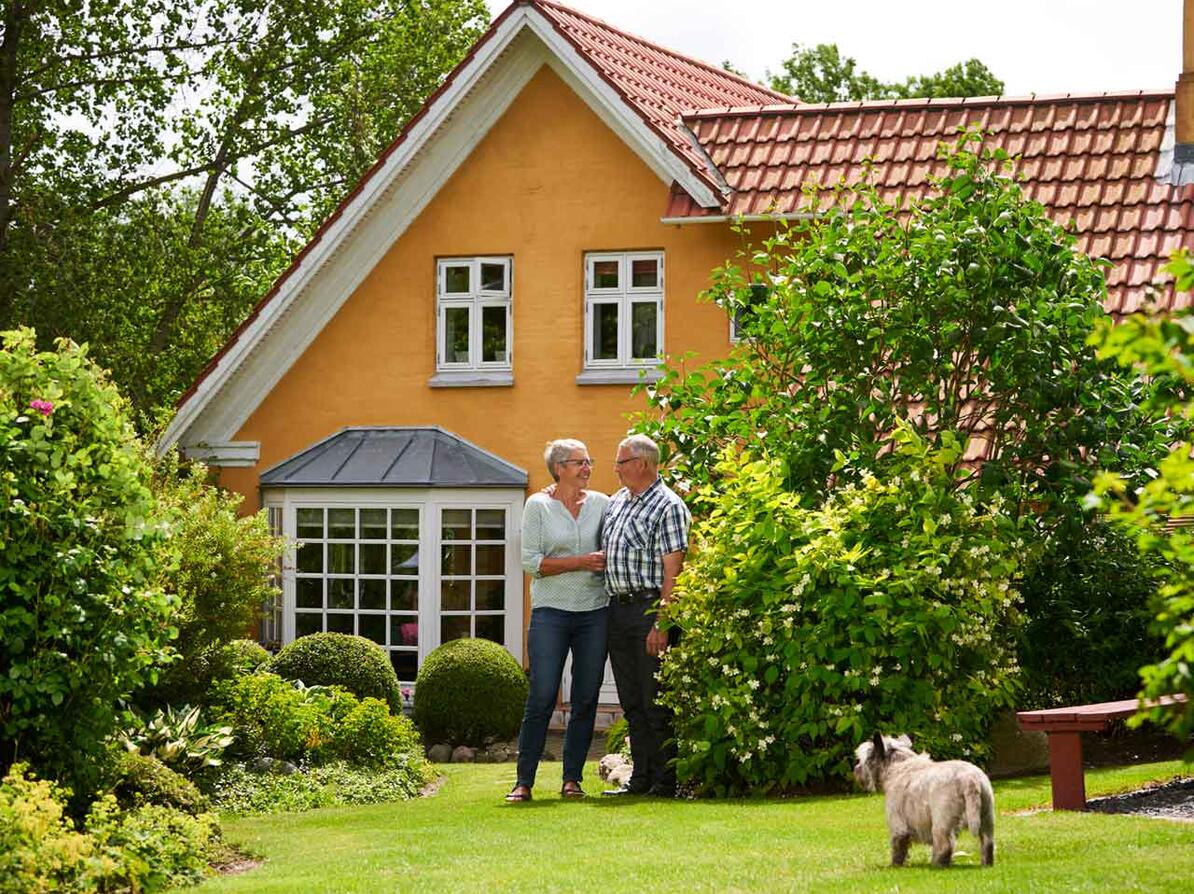 Ældre par foran deres hus med friværdi