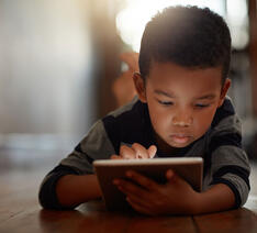 Barn der kigger på en tablet og er på nettet