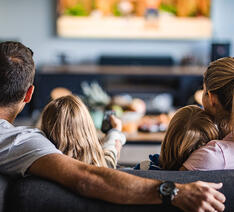 Familie der ser tv og har indstillet tv'et så billedkvaliteten er god.