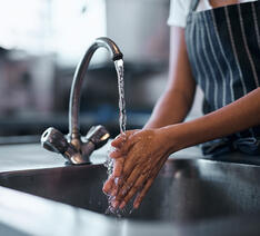 Person vasker hænder i en håndvask med blødgøringsanlæg