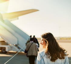 Kvinde på vej op i fly med sit blå sygesikringskort