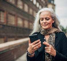 Kvinde kigger på sin telefon fordi hun har modtaget en svindelbesked