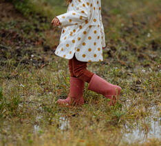 Barn går i et vådt område med gummistøvler på