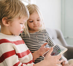 To børn sidder og kigger på en tablet