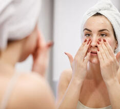 Kvinde smører ansigtscreme i ansigtet 
