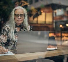 Kvinde sidder med sin computer på en cafe
