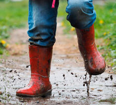 Barn med gummistøvler på, leger i en mudderpøl