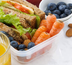 Sund madpakke med sandwich af fuldkornsbrød ved siden af gulerødder og blåbær. 