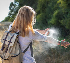 Kvinde sprøjter myggespray på sin arm