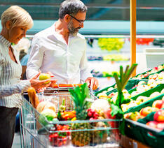 En mand og en kvinde køber grøntsager ind i et supermarked