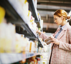 Kvinde kigger på varer på en hylde i supermarked. 