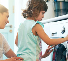 Mor og barn står ved vaskemaskine og håber at autodosering af sæbe fungerer