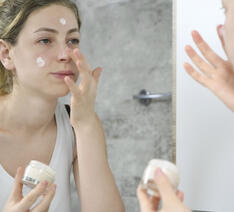 Kvinde smører creme i ansigtet