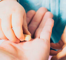Et barn tager en pille fra en hånd - denne kan måske indeholde BHT, hvilket man skal skal undgå