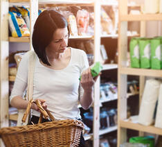 Kvinde står og kigger på emballagen på et produkt i et supermarked