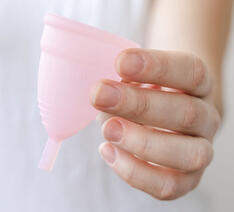 Kvinde holder en menstruationskop