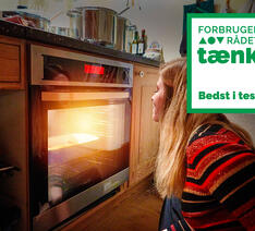 En person sidder ved en ovn og bedst i test logo