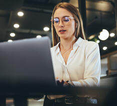 Kvinde med briller kigger på en bærbar computer 