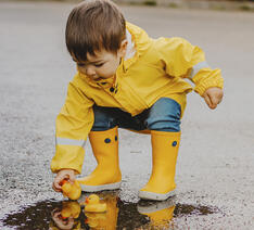 Dreng med gummistøvler på i regnen