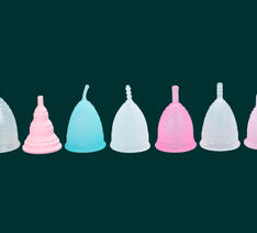 7 menstruationskopper i forskellige farver på række