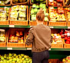 Kvinde kigger på væg med frugt og grøntsager der både er med og uden sprøjtemidler