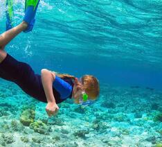 Pige dykker ned mod havbunden. Miljøvenlig solcreme beskytter havmiljøet