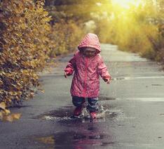 Barn leger i regnen iført regntøj
