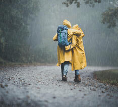to personer går i regnvejr iført gule regnjakker