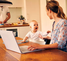 Kvinde sidder med computeren og taler med sit barn