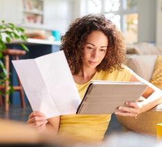 kvinde kigger på papir og tablet med informationer om en investerinsforening