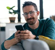 Mand med mobiltelefon ser skeptisk på en sms