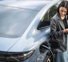 Kvinde står ved elbil, som er ved at blive opladet