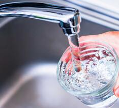 Vand kommer ud af vandhane og ned i glas