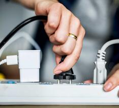 Hånd stikker stik i stikkontakt