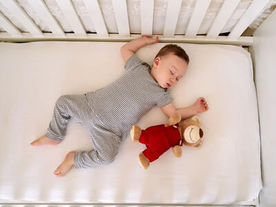 Baby og bamse ligger i sengen
