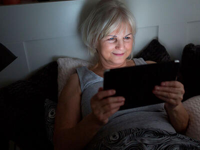 Kvinde læser E-bog på sin tablet men skærmen kan skade hendes søvn. t