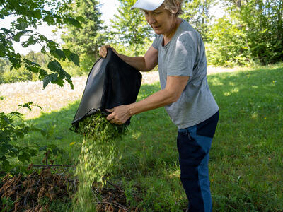Kvinde hælder haveaffald ud i sin have og er klimavenlig