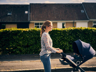 Kvinde går tur med baby i en kombivogn