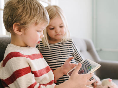 To børn sidder og kigger på en tablet