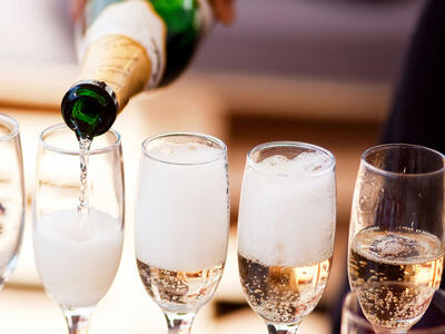 Mousserende vin bliver hældt op i champagneglas.