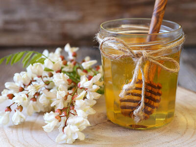 glas med honning ved siden af honningblomster.