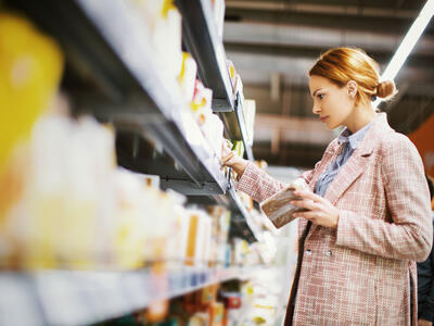 Kvinde kigger på varer på en hylde i supermarked. 