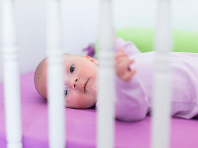 Baby ligger i en tremmeseng
