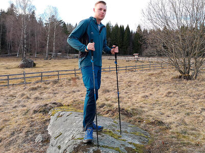 En mand står på en sten med sine vandrestave